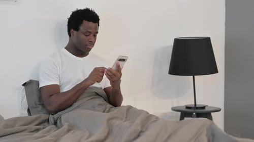 Man in Bed Using Cellphone