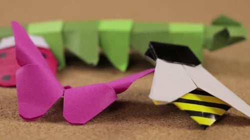 Paper bugs made with the origami technique. Cork surface for crafts. Close up. Long video.