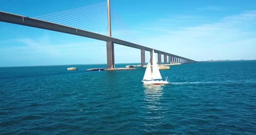 4K-Luft-Slomo-Video eines Segelboots, das sich einer Seilhängebrücke nähert
