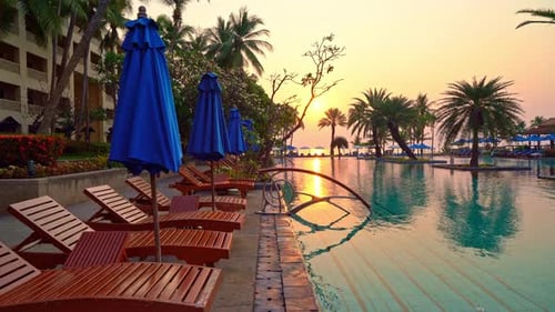 bed pool and umbrella around swimming pool with sunset or sunrise sky