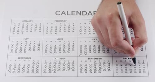 Hand Marking Dates on Paper Calendar