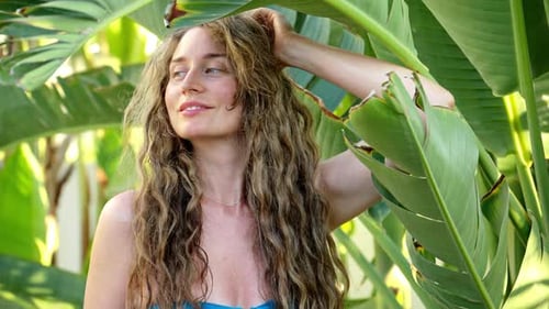 Woman playing with palm tree leaves at the beach in Cyprus, hiding