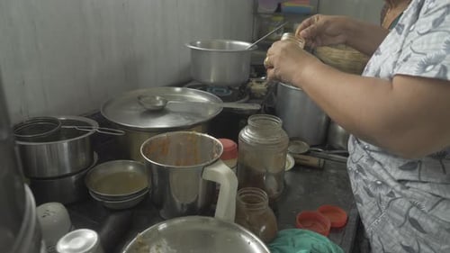 Adults Prepare Food in Messy Kitchen with Jars