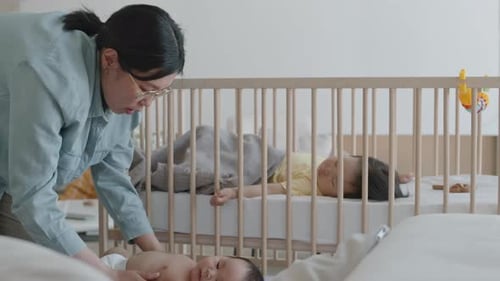 Une maman asiatique renforce les muscles de son bébé en faisant un massage des jambes