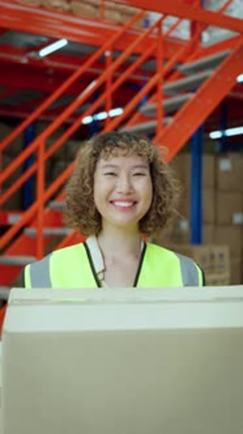 Cheerful warehouse worker holding a cardboard box
