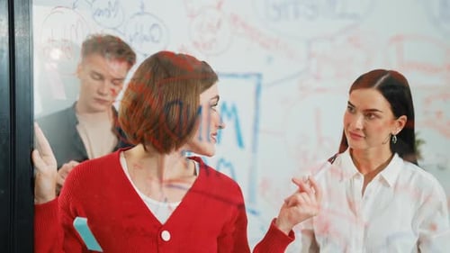 Team Brainstorming Ideas on Glass Board in Office