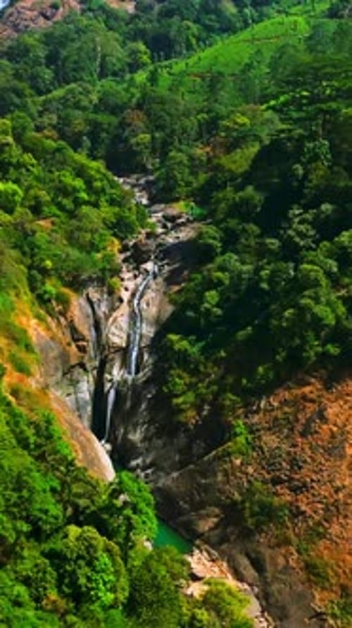 Drone vertical filmé autour d'une cascade dans les montagnes de Munnar, sous le soleil de l'Inde