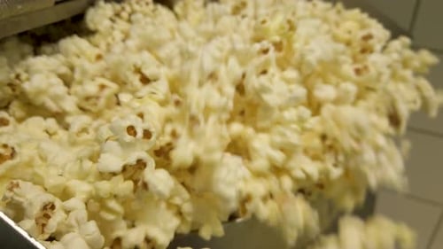 Tilt shot of a Cascade of Popcorn Bursts Forth from the Industrial Popcorn