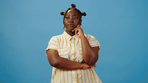 Woman Thoughtfully Posing in Studio Against Blue Background