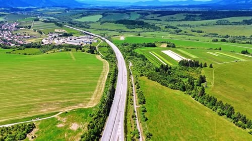 Kurvenreiche Straße durch grüne Felder. Eine Autobahn schlängelt sich durch üppige grüne Felder