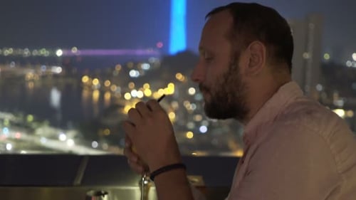 Young Man Relaxing and Drinking Cocktail Sitting on Terrace in Bar At