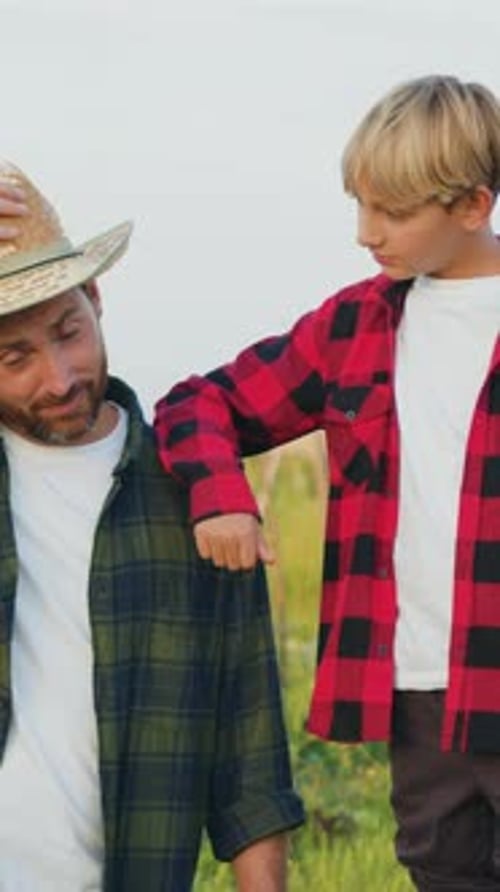 Retrato de un campesino caucásico sonriente, un trabajador se pone el sombrero y choca los cinco con su hijo en