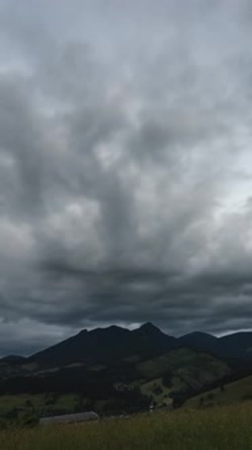 Vidéo verticale de nuages sombres et dramatiques se déplaçant rapidement au-dessus des montagnes (Lap de temps)