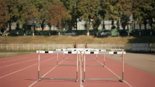 Athletes Training, Running and Jumping Over Hurdles