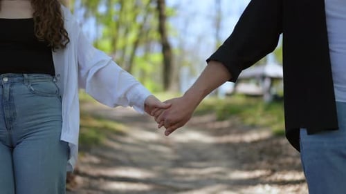 A Romantic Couple Holding Hands While Walking Together Along a Beautiful Nature Path