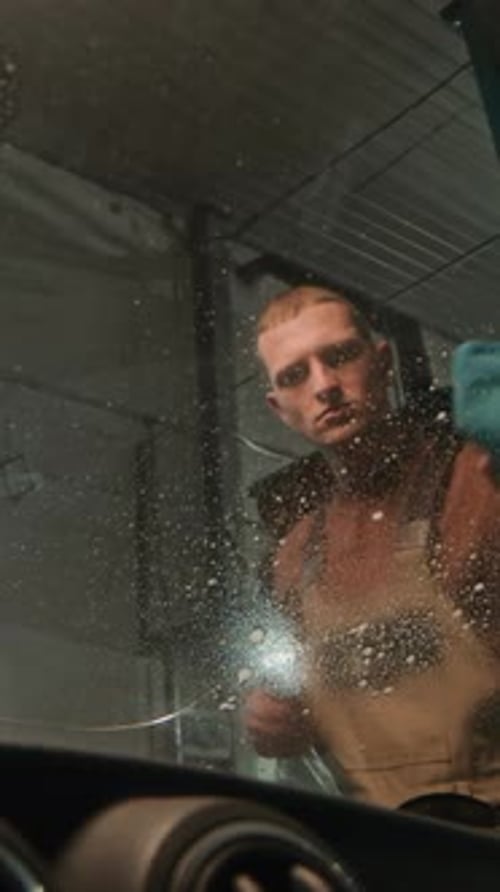 Specialist Using Spray to Clean Windscreen of Automobile