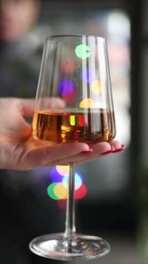 A girl holds a glass of wine. Close-up