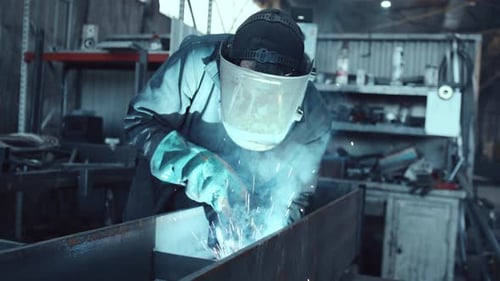 Professional welder joining steel beams with sparks