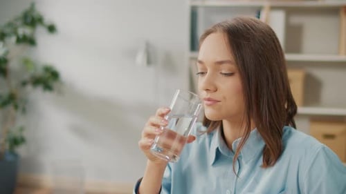 Büroangestellte trinkt in einer Pause zwischen der Arbeit ein Glas sauberes Wasser
