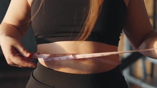 Woman Measures Waist with Tape Measure