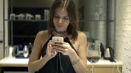 Woman Texting On Smartphone Sitting In Cafe At Night