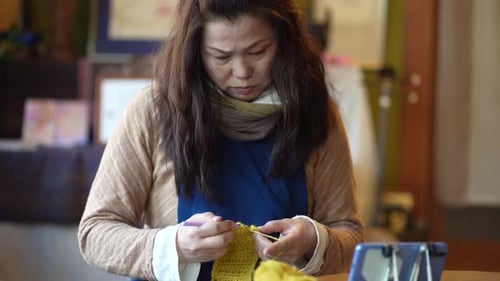 Woman Crocheting Yellow Yarn at Home During the Day
