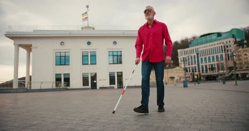 Senior Blind Man with White Cane Walking Across the Street in City