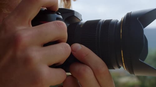 Photographer Adjusting Zoom Lens on Camera Outside