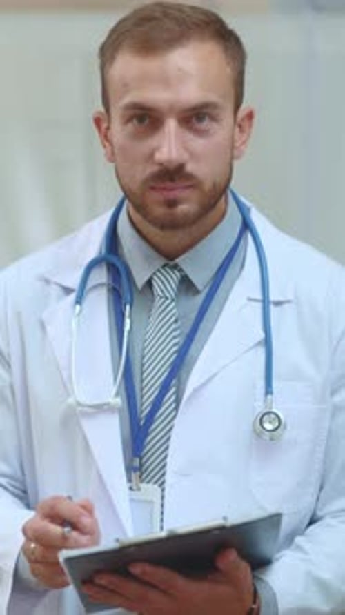 Porträt eines positiven kaukasischen jungen erfolgreichen Arztes, der in seinem privaten Gesundheitswesen in die Kamera lächelt