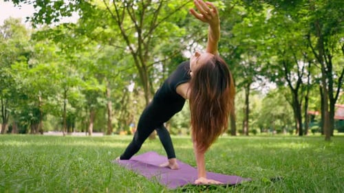 an experienced female instructor meditates in the park practices yoga does stretching and exercises