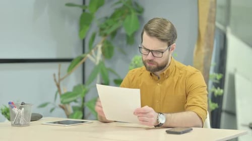 Adult Man Reviews Document at Office Desk