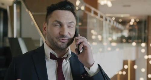 Portrait of Successful Businessperson in Suit Speaking on Mobile Phone From Luxurious Hotel Lobby