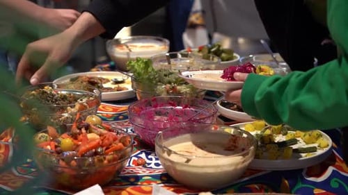 A group of people picking up salad for their food, close up shot, high angle shot