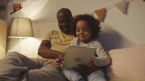 Man and Child Using Tablet at Bedtime