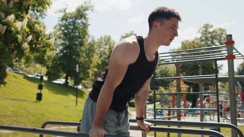 Athletic Caucasian Man in Sportswear Practicing Dips on Parallel Bars Training Triceps on Playground