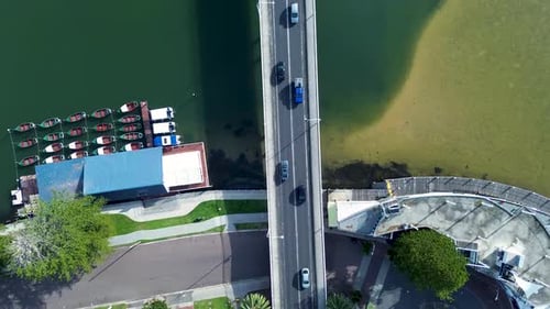 Drone aerial landscape of cars traffic on main road motorway bridge with boats docked at wharf pier