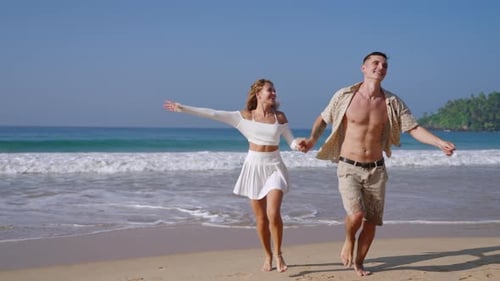 Attractive Couple Run Holding Hands in Sea Surf Waves Tanned Man and Woman Having Fun on Summer