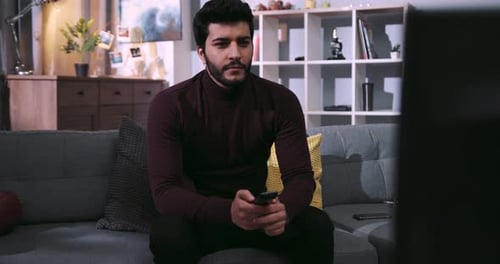 Man relaxing on couch watching TV in living room