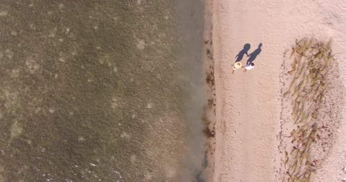 Older couple holding hands walking peaceful tropical beach in beautiful sunlight