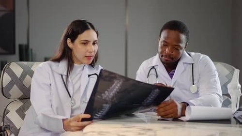 Two diverse doctors collaborate in a medical hospital, examining test results and discussing X-ray