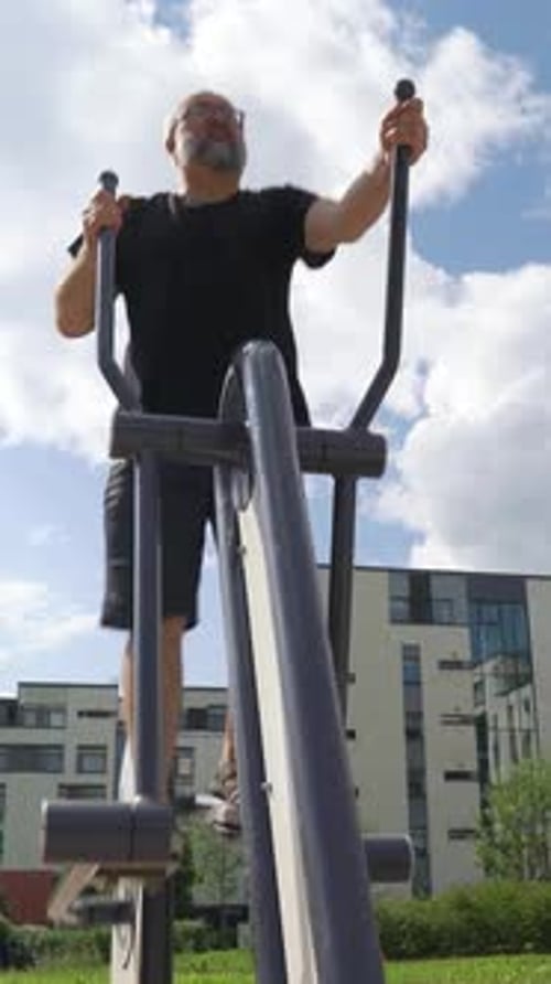 A Mature Man Exercising on Outdoor Fitness Equipment