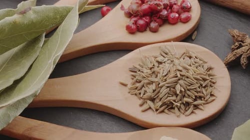 Various types of spices on wooden spoons slowly move along the frame