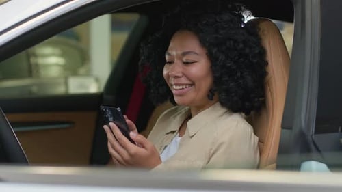Woman Smiling While Using Smartphone Inside Car