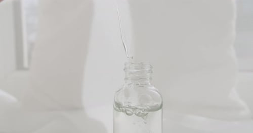 Dropper Drips Clear Liquid in Glass Bottle Close Up