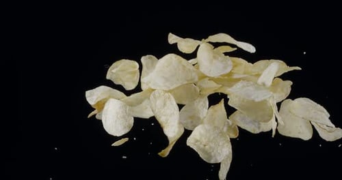 Natural potato chips rise and fall against a black background.