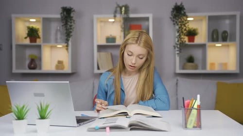 Woman Studying from Book at Desk at Home
