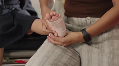 Close up Asian woman helping child with ankle bandage after small injury
