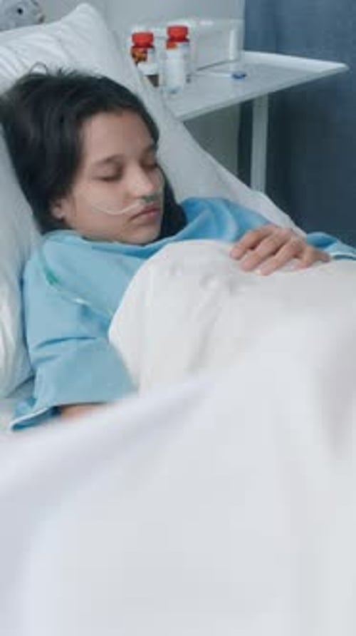 Vertical of Little Girl with Nasal Cannula Being on IV While Sleeping in Ward