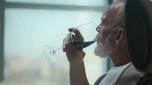 Relaxed Man Sipping Red Wine in Armchair with City View