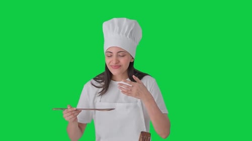 Happy Indian professional chef tasting her food Green screen